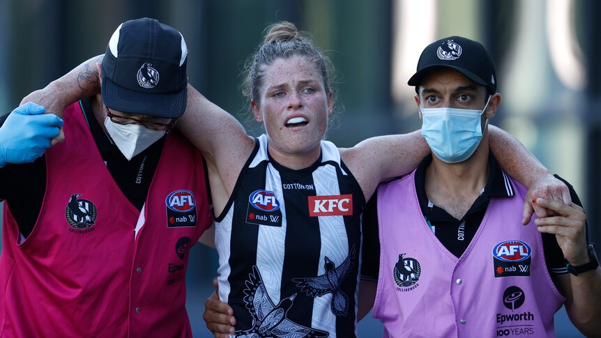 Bri Davey looks distraught as she is helped from the ground by trainers in masks