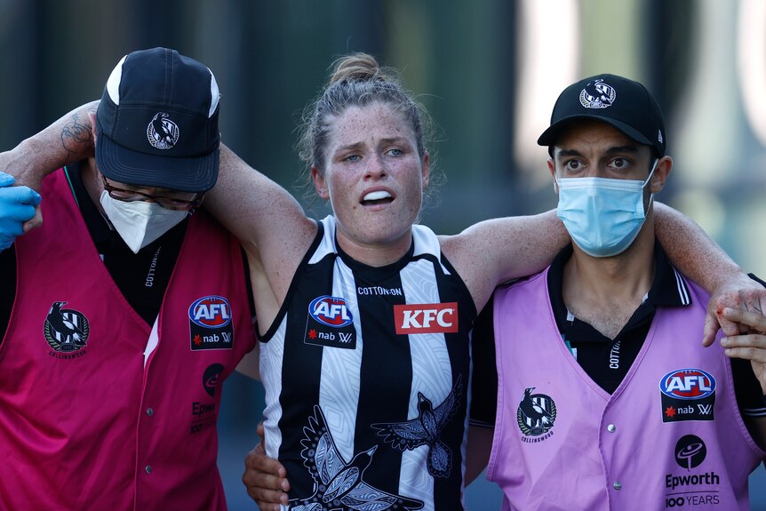 Bri Davey looks distraught as she is helped from the ground by trainers in masks