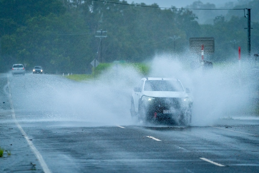 A car splashes water as it drives over a wet road