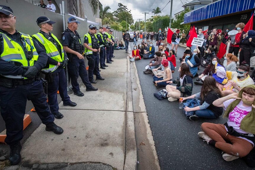 A line of police butt up against hundreds of protesters at Kangaroo Point.
