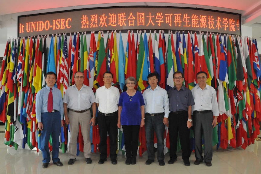 Monica Oliphant part of group photo in front of flags in China.