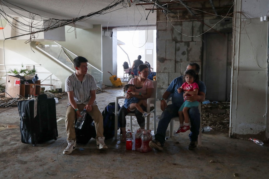 Three tourists sit in a damaged hotel in the aftermath of Hurricane Otis.