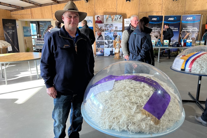 A man wearing a hat standing alongside a dome containing the most valuable fleece at the Campbell Town Show