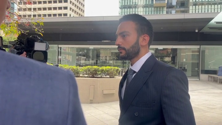 A man with a beard in a suit outside court
