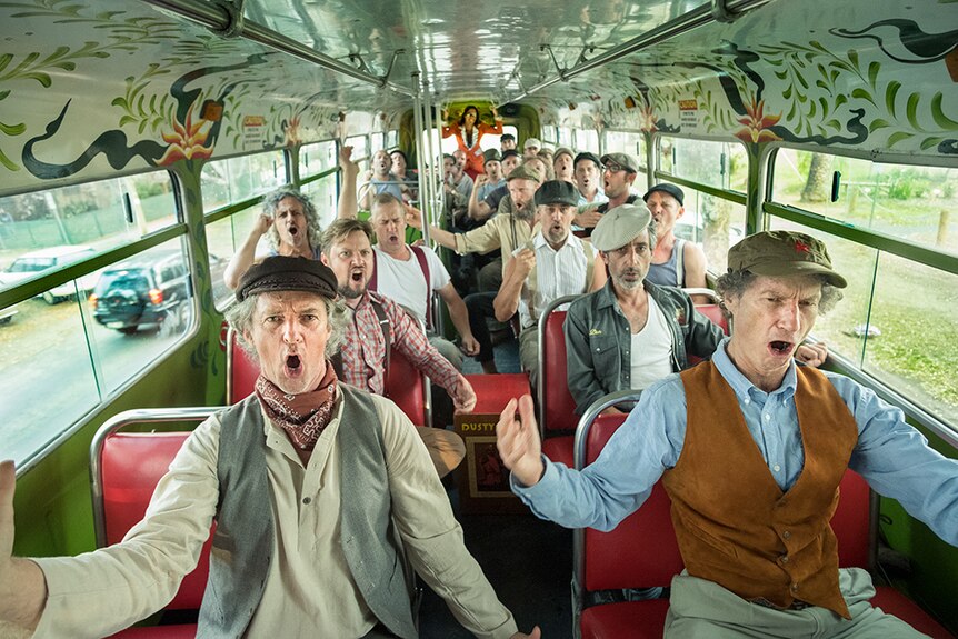 A group of more than 24 men posed mid-singing on a bus