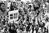 A group of young people holds signs saying "try Jesus" and pointing to the sky