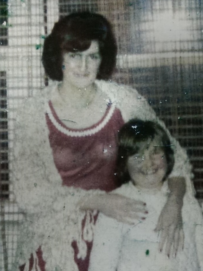 A woman with dark bobbed hair in a dress stands to the left of a little smiling girl 