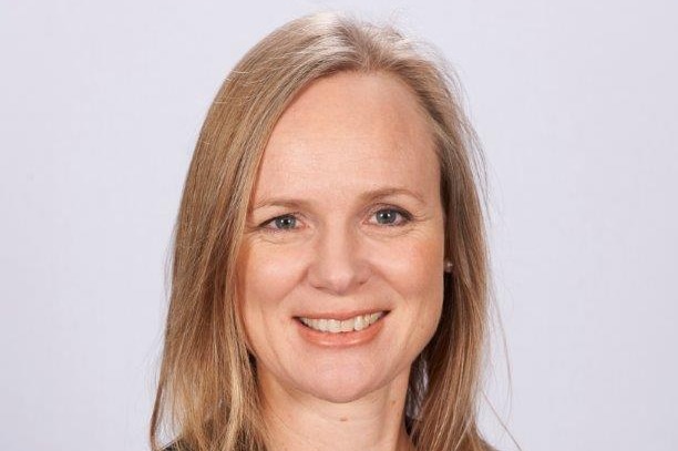 A lady with blonde hair looks at the camera in a professional photo