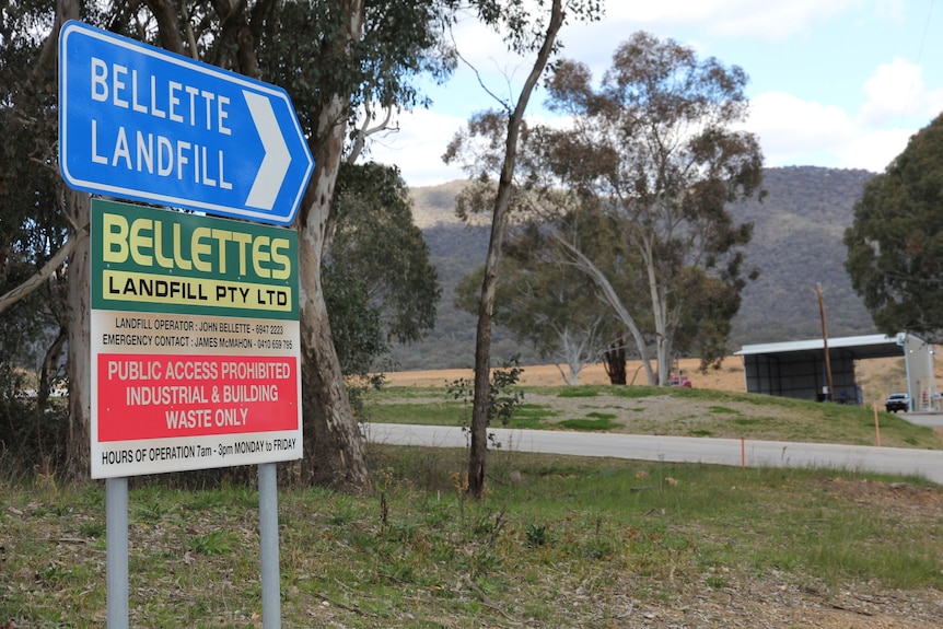 Signs pointing to the entrance of Bellettes Landfill, with the facility visible in the background.