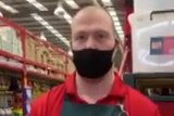 A male Bunnings staff member is wearing a black face mask and standing up