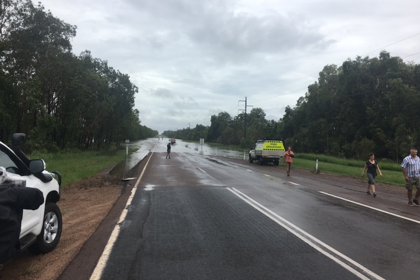 People gather on the Arnhem Highway where the road has been flooded.