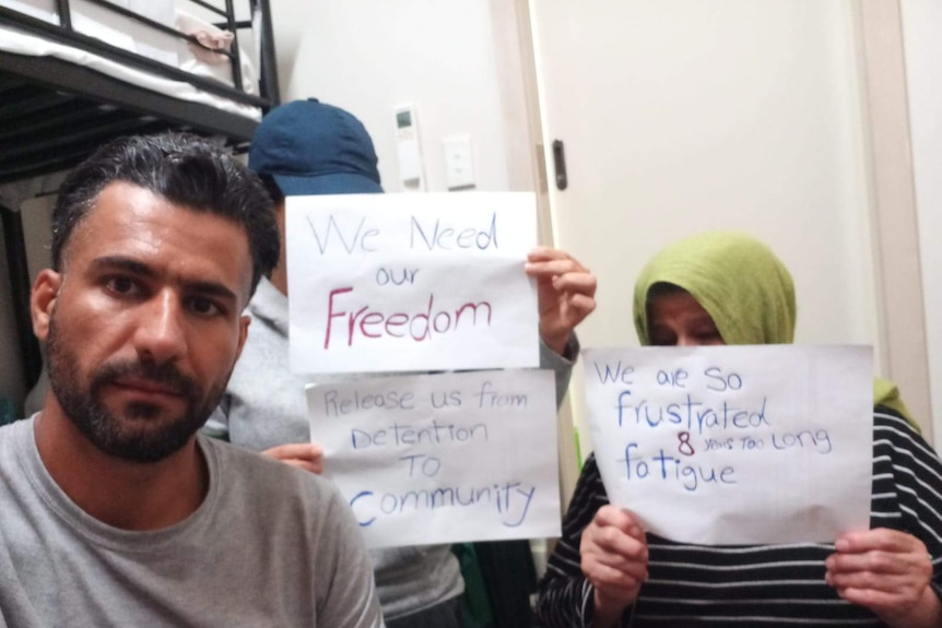 Abbas and his sister and mum holding signed to let them free because they feel like they are in prison but are innocent.