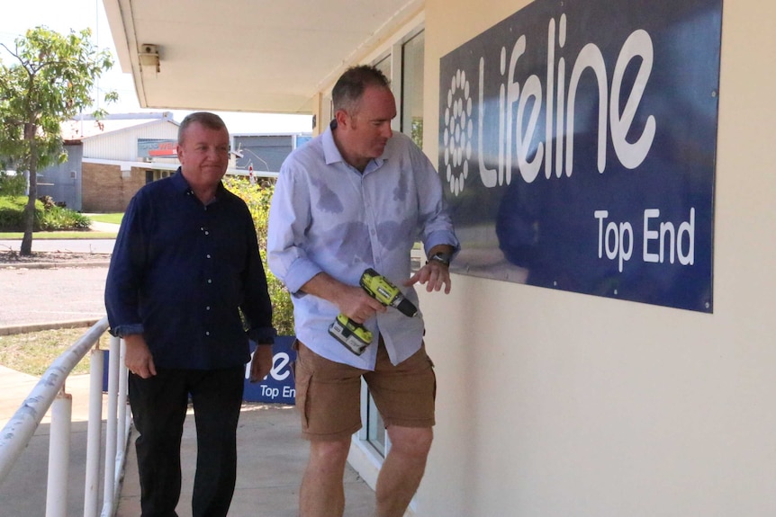 Mark Dodge (left) and Andrew Warton taking down a Lifeline sign at the Top End centre closed