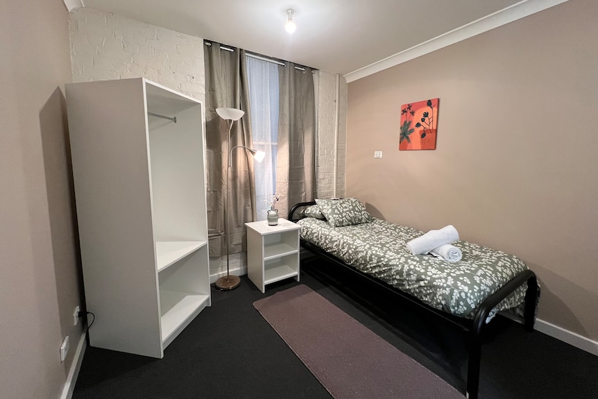 wardrobe, desk, and bed inside room at Reid's Guest House Ballarat