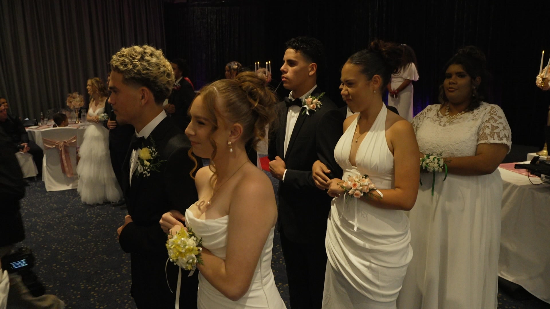 male and female couples dressed in suits and dresses form a line