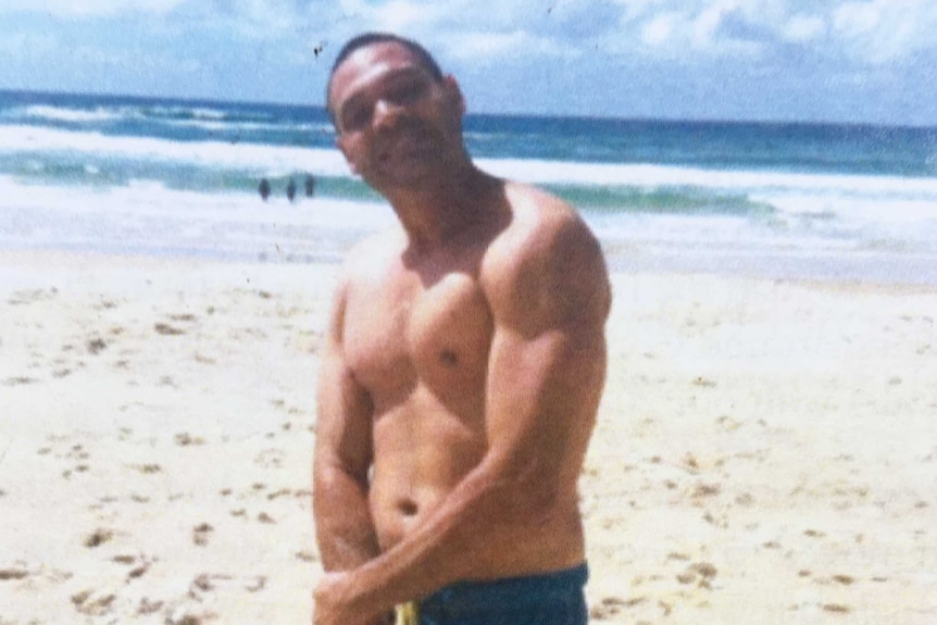 Shaun Charles Coolwell stands and smiles on a beach on a sunny day, location and date unknown.