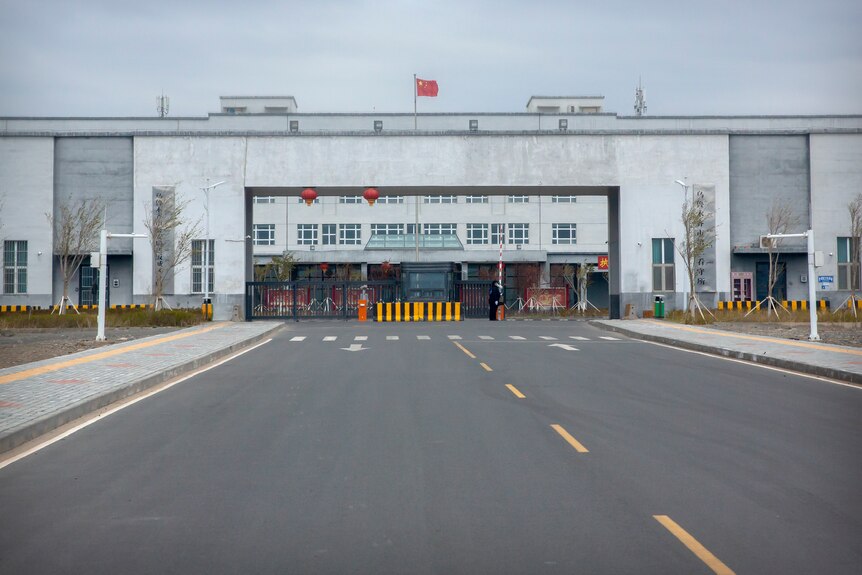 Police officers stand outside a large detention centre adorned with Chinese flags