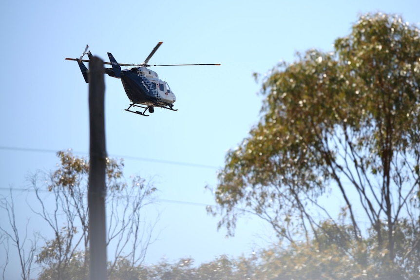 A police chopper flies along a skyline