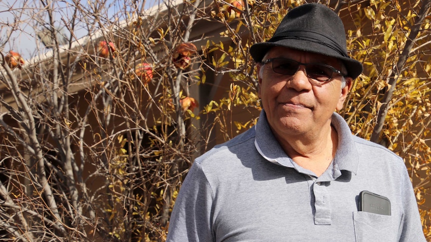 Kalgoorlie Aboriginal elder Trevor Donaldson stands in front of a pomegranate tree.