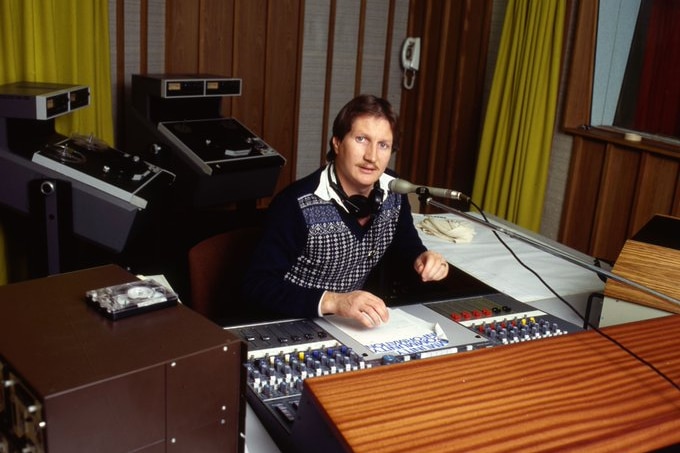 A man sitting in a radio studio behind a microphone