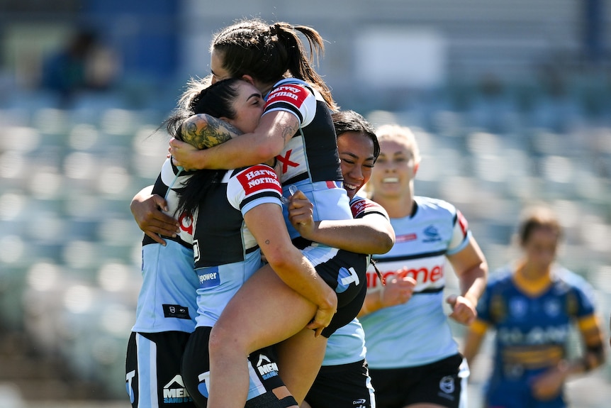 An NRLW tryscorer for Cronulla jumps into the arms of a teammate in celebration.