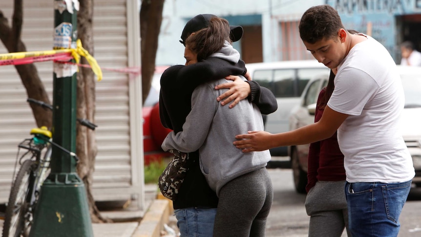 Residents hug after a building was damaged by an earthquake that struck off the southern coast of Mexico