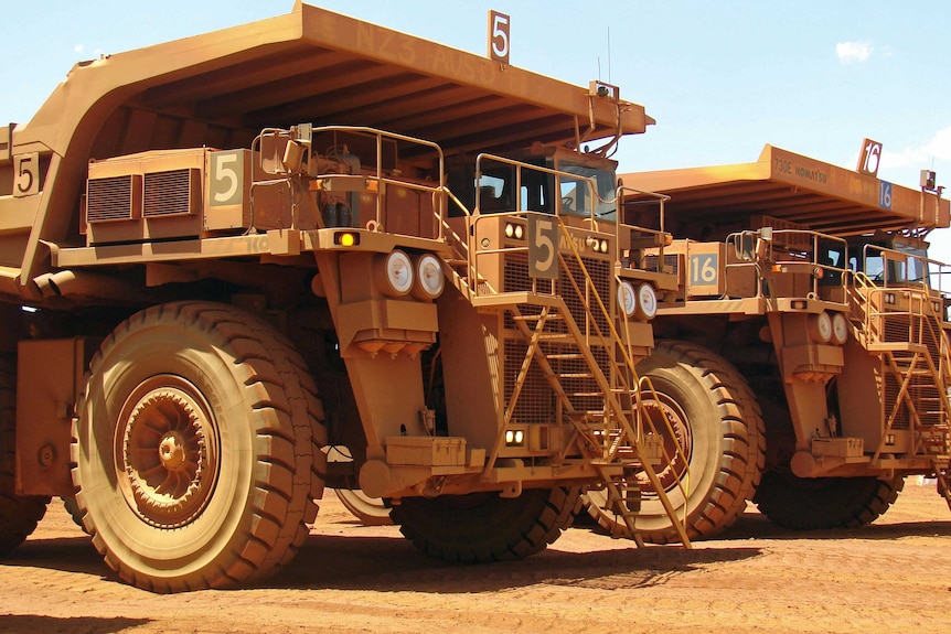 Image of heavy trucks lined up at a mine site.