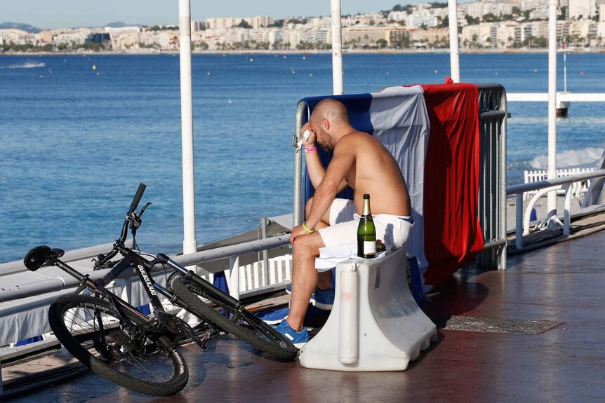 A man reacts as he sits near a French in Nice