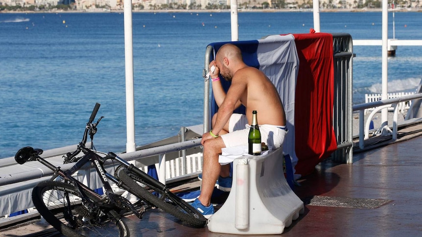 A man reacts as he sits near a French in Nice