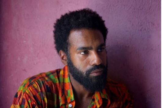 Heritier Lumumba, wearing an orange and green shirt, poses for a portrait