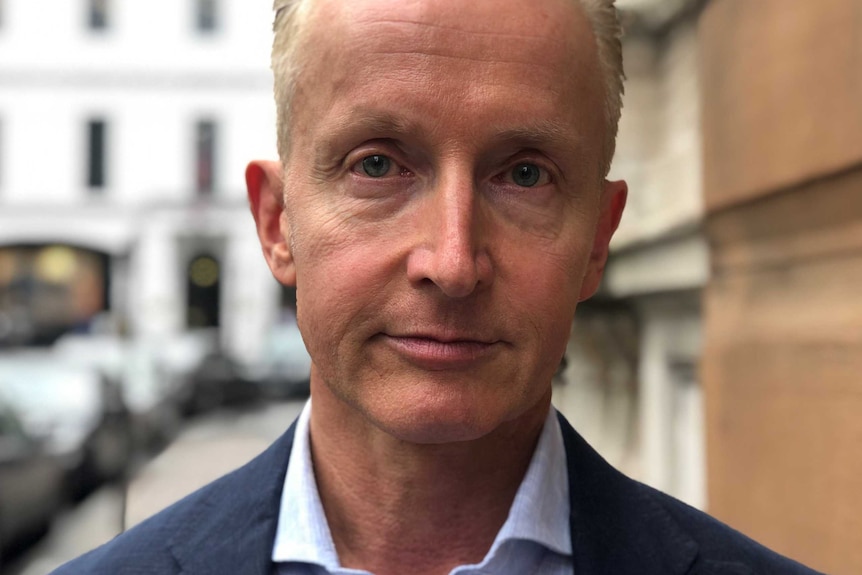 A man standing on a London street looking serious