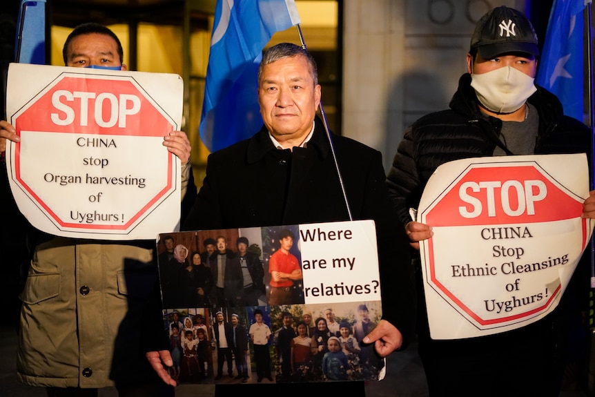 Los manifestantes sostienen pancartas y banderas durante una manifestación frente a la embajada china.