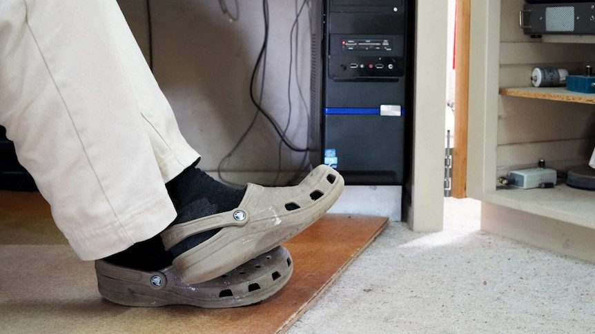 Tony Hutchison's crocs rest under his radio desk.
