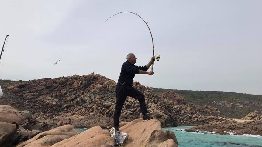 Steven stands on a rock casting a fishing line.