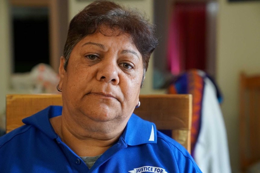 Lewis "Buddy" Kelly's sister Tanya looks into the camera while sitting on a chair in a family home.