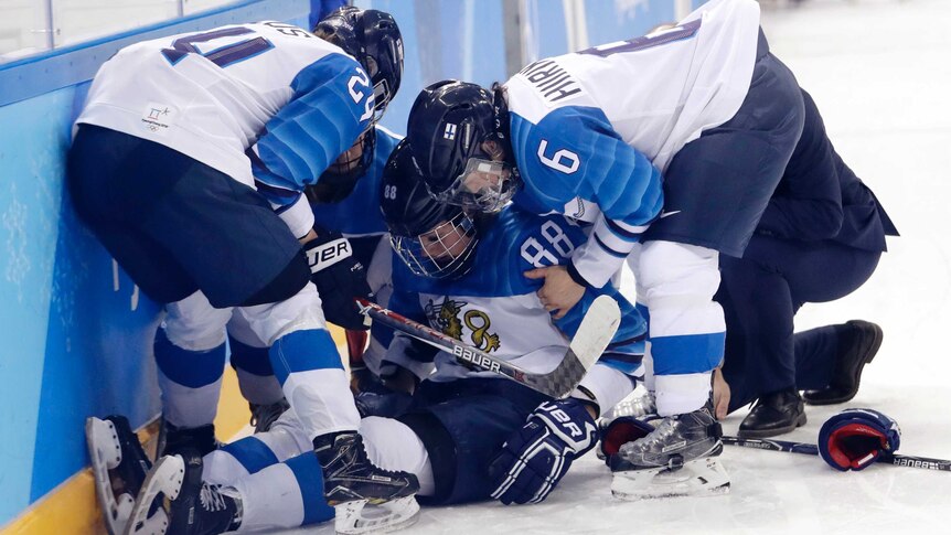 Ronja Savolainen is helped by her teammates on the ice after her crash.