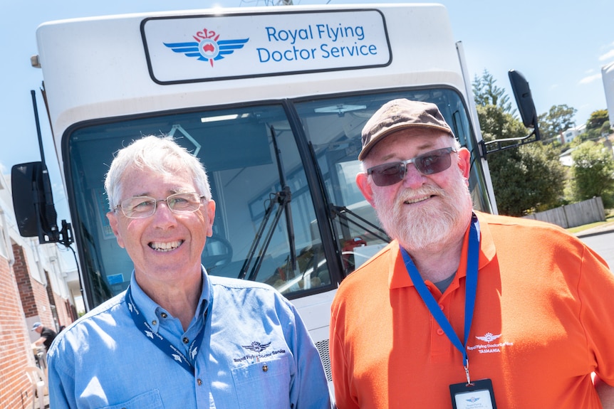 Two men stand in front of Royal Flying Doctors Service bus.