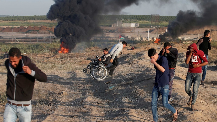 A wheelchair-bound Palestinian photographer is helped.