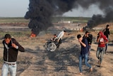 A wheelchair-bound Palestinian photographer is helped.