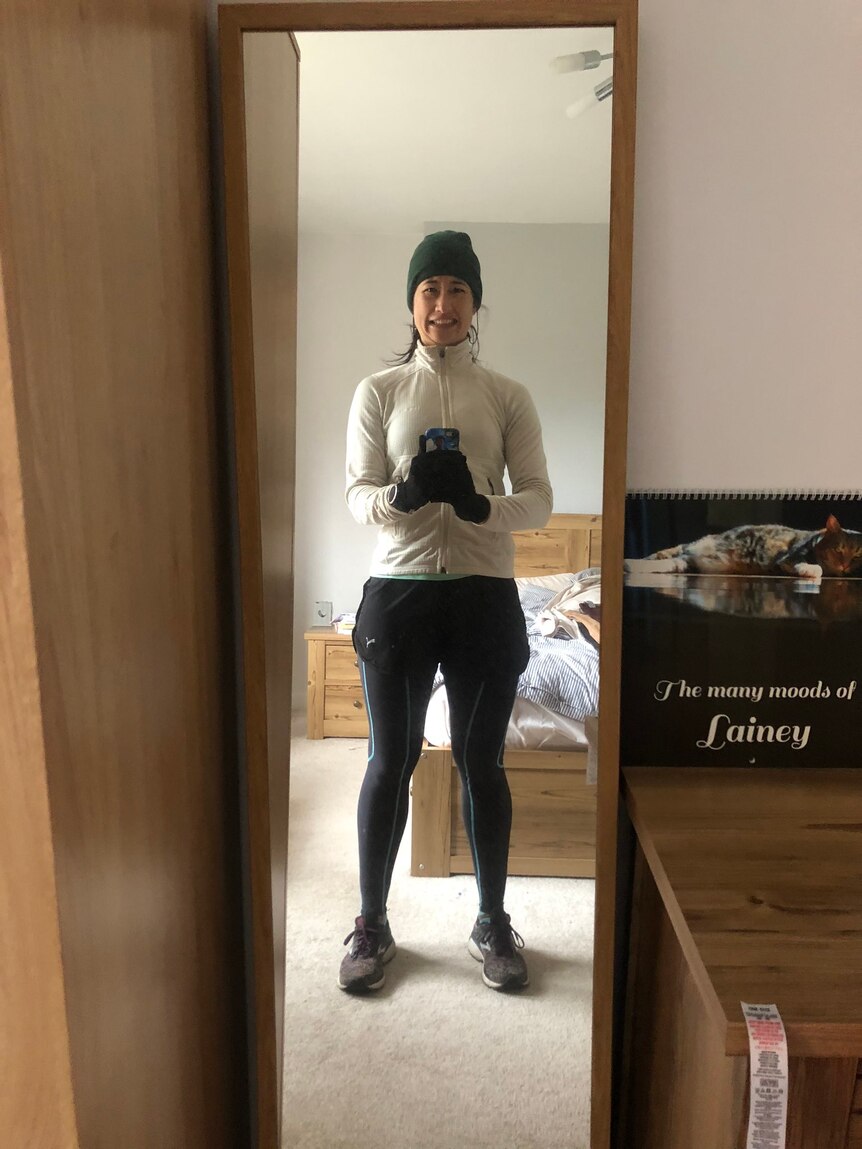Belinda Smith takes a selfie of herself dressed in running gear and a beanie in a Glasgow apartment
