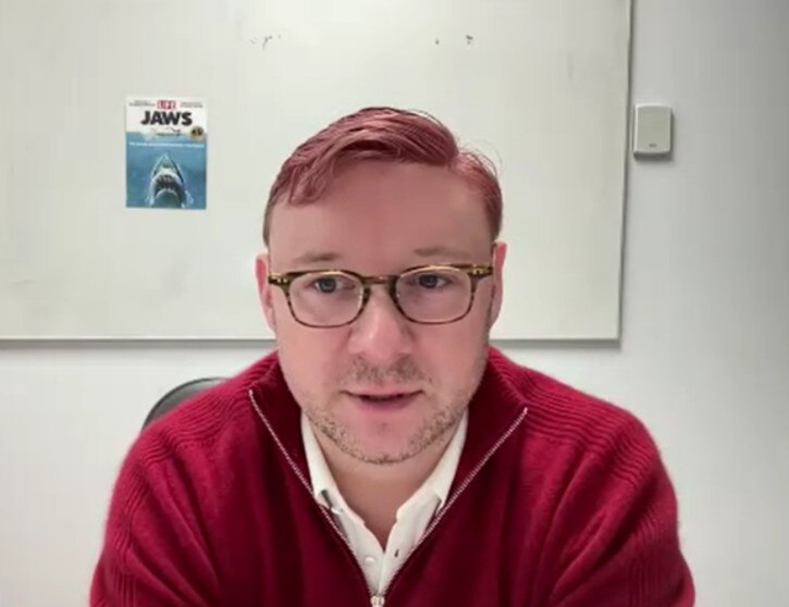 A man wearing glasses and a red jumper.