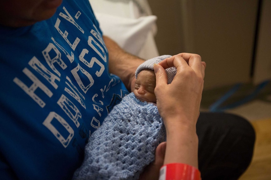 Zayden being cradled by his parents