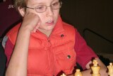 Young chess player Anton Smirnov studies the board.