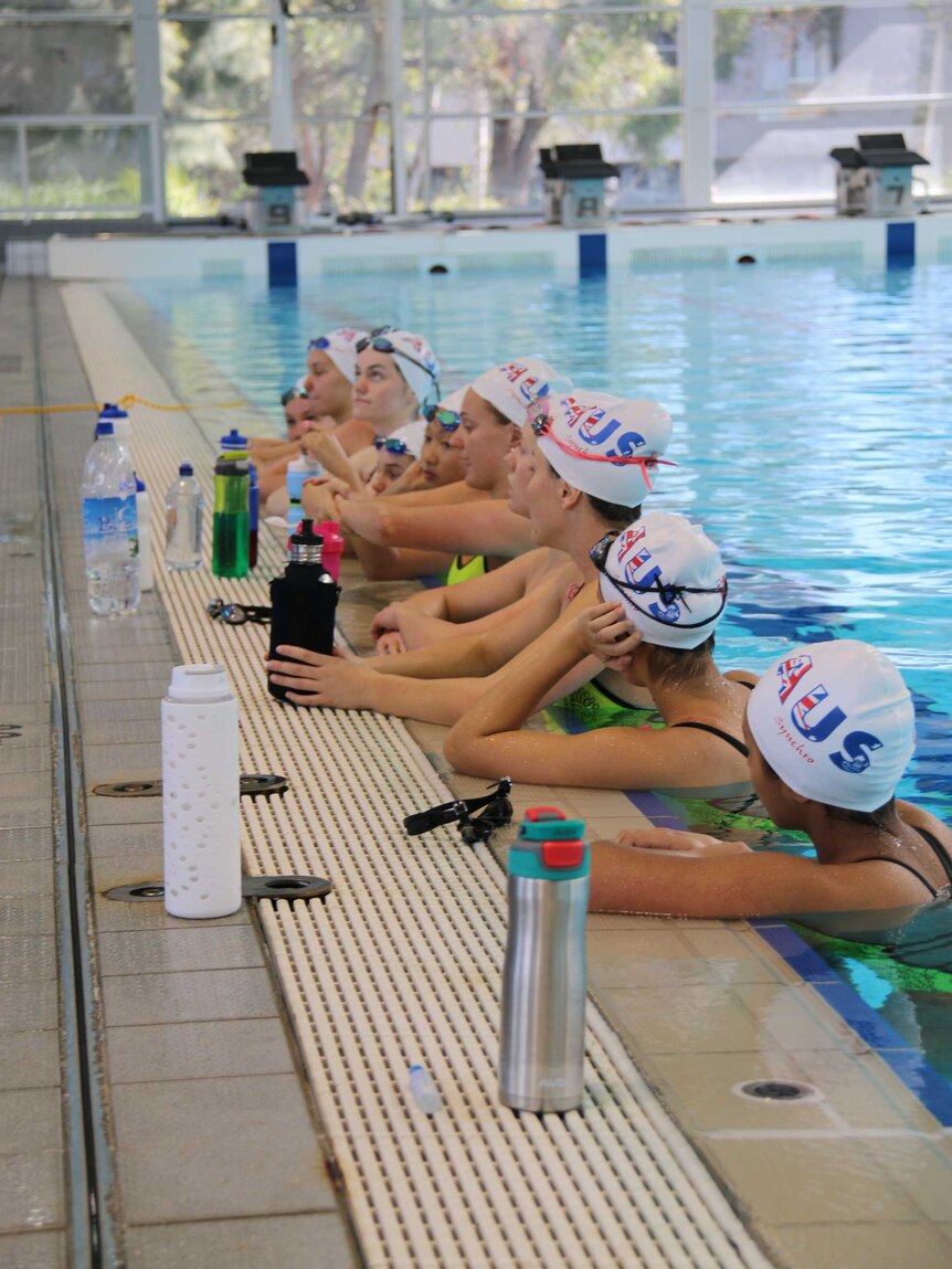 The team listen to coach Leslie Sproule for feedback.