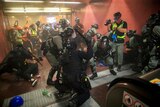 In a subway station, police swarm protesters and beat them with batons in front of escalators.