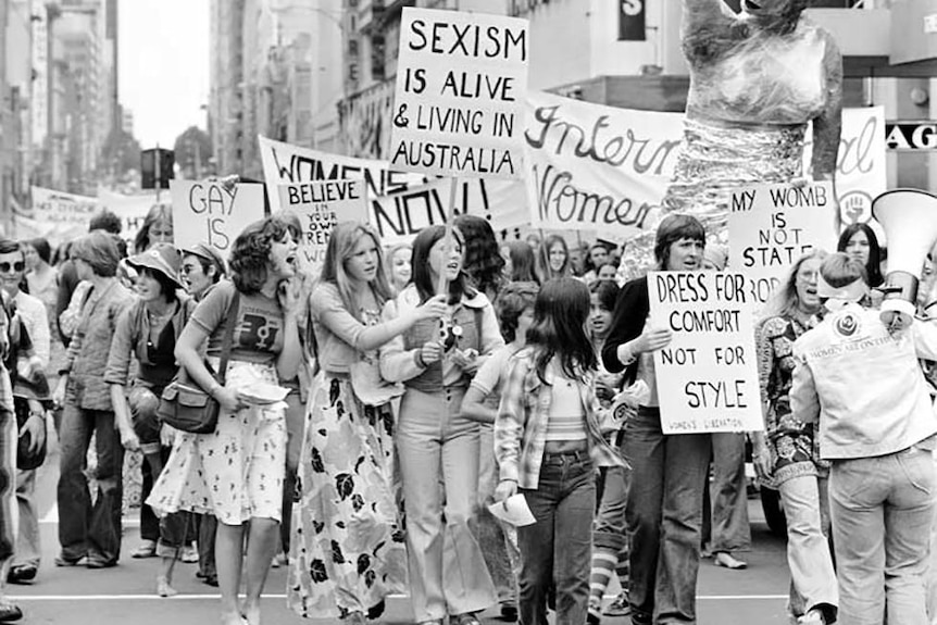 A black and white photo of women with signs protesting in the street.