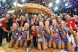 NSW Swifts players smile for a victory photo with a gold trophy
