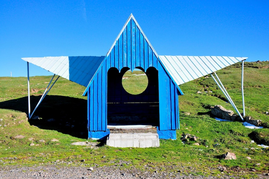 A blue bus stop with a pointed high roof