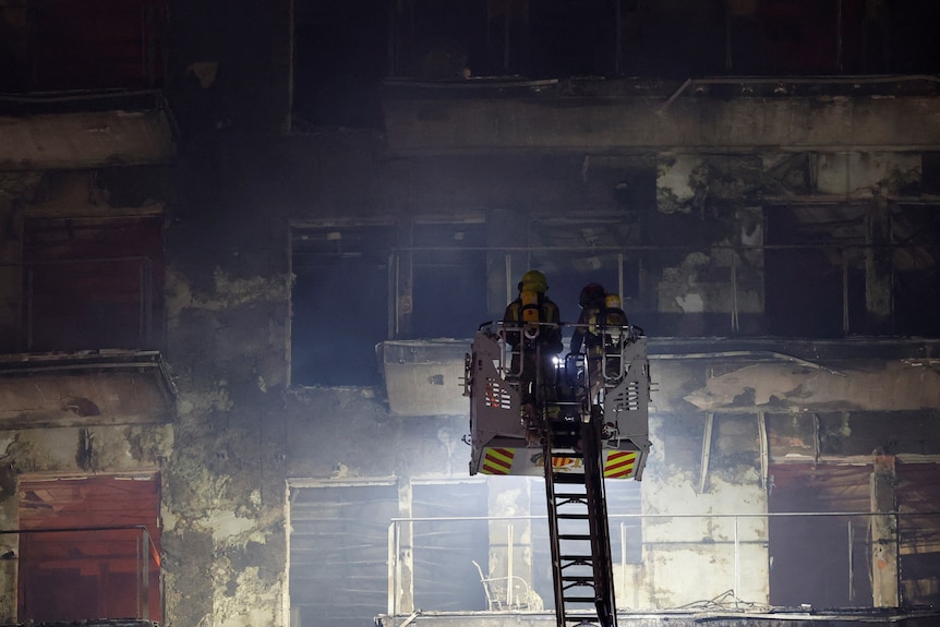Firefighters look on at the scene of a fire on an apartment building in Valencia, Spain.