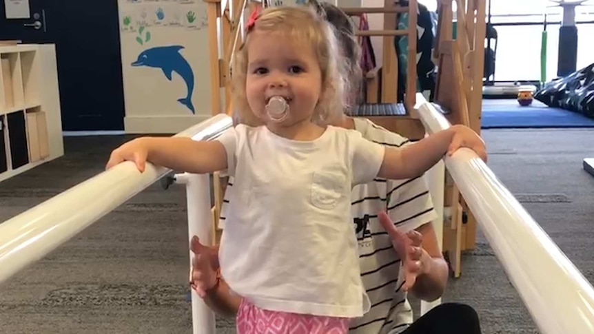 Matilda Donald holds on to bars as she walks.